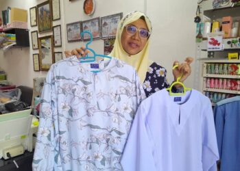 HASNAH MAHMOOD menunjukkan antara tempahan baju sekolah dan baju raya yang telah disiapkannya.