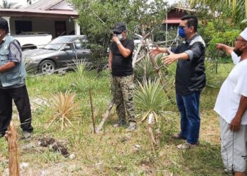 KHAIRULAZNI Baharuddin (dua dari kanan) memperkatakan sesuatu kepada seorang anggota Perhilitan sewaktu meninjau kebun seorang penduduk yang dimusnahkan babi hutan di Kampung Kelongkong, Tanjung Kling, Melaka. - UTUSAN/AMRAN MULUP