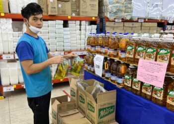 SEORANG pekerja sebuah sebuah pasar raya menunjukkan minyak masak peket yang dijual di pasar raya berkenaan ketika tinjauan Utusan Malaysia di Senawang, Negeri Sembilan. - UTUSAN/ZAKKINA WATI AHMAD TARMIZI