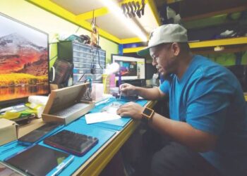 MOHD Idris Mazlan membaiki telefon bimbit pelanggannya di Kampung Kubang Bunut, Pasir Mas, Kelantan hari ini. - UTUSAN/YATIMIN ABDULLAH
