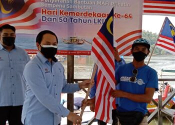 MOHAMAD Rizal Sahari (dua dari kiri) menyampaikan bantuan bakul makanan dan mengagihkan Jalur Gemilang kepada nelayan di Jeti Nelayan Batu 3 Segari dekat Lumut, Perak, hari ini. 