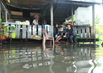 SEBUAH keluarga terpaksa berteduh di sebuah pondok berhampiran selepas kediaman mereka dinaiki air sehingga paras lutut di Kampung Bakau, Kangar, Perlis hari ini.- UTUSAN/IZLIZAN OTHMAN