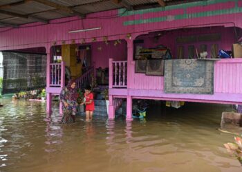 Samsiah Muda, 63, dan cucunya mengalihkan pasu bunga ke kawasan lebih tinggi berikutan banjir kilat di Kampung Telaga batin,Kuala Nerus, Kuala Terengganu, hari ini.
