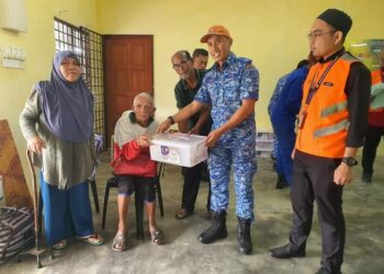 ANGGOTA APM dan petugas JPKK Daerah menyampaikan bantuan barang makanan kepada seorang mangsa di sebuah PPS di Rompin, Pahang. - FOTO/ IHSAN JKM ROMPIN