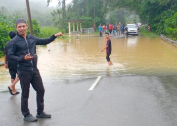 BEBERAPA orang penduduk sedang melihat air melimpah di jalan Batu Langguk, Kuala Tembeling di Jerantut, Pahang. - FOTO/IHSAN PENGGUNA JALAN RAYA