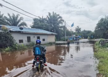 PENDUDUK meredah banjir untuk keluar masuk ke kampung mereka di Batu 7, Jalan Changkat Jong di Teluk Intan, Perak. - UTUSAN/AIN SAFRE BIDIN