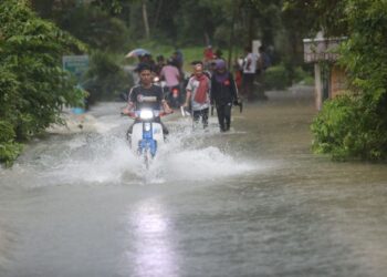 PENDUDUK meredah jalan yang dinaiki air
di Kampung Titian Baru di Marang, Terengganu. - UTUSAN/PUQTRA HAIRRY ROSLI