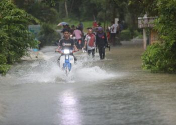 PENDUDUK meredah jalan yang dinaiki air
di Kampung Titian Baru di Marang, Terengganu. - UTUSAN/PUQTRA HAIRRY ROSLI
