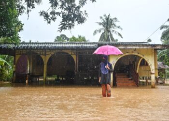 SEORANG penduduk, Rasyikin Hassan meninjau pekarangan rumahnya yang dinaiki air  di Kampung Nibong, Hulu Terengganu, Terengganu, hari ini. - UTUSAN/PUQTRA HAIRRY ROSLI