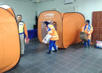 ANGGOTA APM memasang khemah untuk menempatkan tujuh mangsa banjir di PPS balai raya Bandar Perwira Jaya di Rompin, Pahang. - FOTO/IHSAN APM PAHANG