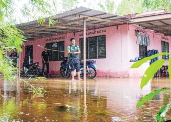 MUHAMMAD Zafrul Hakim Zaimi mencuba nasib memancing dalam banjir termenung di hadapan rumahnya di Kampung Parit Senin, Jasin, Melaka. – UTUSAN/SYAFEEQ AHMAD