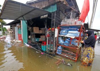 SEORANG peniaga kedai runcit mengalihkan barang-barang perniagaannya ke tempat lebih tinggi ekoran banjir di Kampung Senor, Pasir Mas, Kelantan. -UTUSAN/ZULHANIFA SIDEK