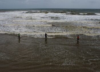 TIGA nelayan menjala ikan di pesisir pantai dalam keadaan laut bergelora pada musim tengkujuh di Pantai Pandak, Chendering, Kuala Terengganu, Terengganu. - UTUSAN/PUQTRA HAIRRY ROSLI