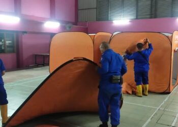 PARA petugas menyediakan kemudahan di Pusat Pemindahan Sementara (PPS) dibuka di SK Sri Klebang bagi menempatkan mangsa banjir dari RPT Kampung Chepor, Ipoh. - UTUSAN
