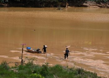PENDUDUK meredah lumpur di Sungai Kampung Dusun berikutan air surut kerana penutupan sementara operasi Empangan Hidro di Stesen Janakuasa Kenyir Tenaga Nasional Berhad (TNB)  susulan tanah runtuh di Jenagor, Kuala Berang, Terengganu. - UTUSAN/PUQTRA HAIRRY