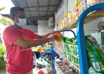 M. ULAGANATHAN menyusun bekalan bank makanan di depan rumahnya di Ujong Pasir, Melaka. - UTUSAN/MUHAMMAD SHAHIZAM TAZALI