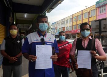 S. Hassan Kuthoos (dua dari kiri) menunjukkan laporan polis berhubung bantahan penamatan PKPD di asrama pekerja Top Glove  di Balai Polis Meru, Klang, Selangor, semalam. - UTUSAN/ISKANDAR SHAH MOHAMED