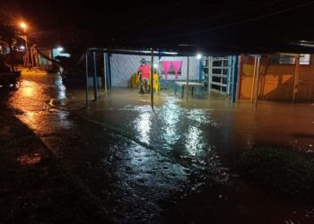 SEORANG pemilik kedai kopi sedang mengemaskan kerusi meja berikutan air Sungai Tembeling melimpah masuk di dataran perniagaan Kampung Bantal, Ulu Tembeling di Jerantut, Pahang. - FOTO/HARIS FADILAH AHMAD