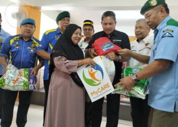 ZAMBERY Jefry Darus (tengah) menyampaikan kit bantuan banjir kepada salah seorang penerima di Masjid Baiturrahman Kampung Gual Nering Rantau Panjang, Kelantan. -UTUSAN/ROHANA ISMAIL.