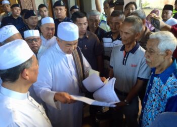 AHMAD Zahid Hamidi (dua, kiri) meneliti memorandum yang diserahkan wakil penduduk, Mohd. Yatim Hashim (dua, kanan) di Lapangan Terbang Sultan Mahmud, Kuala Nerus, petang tadi. 