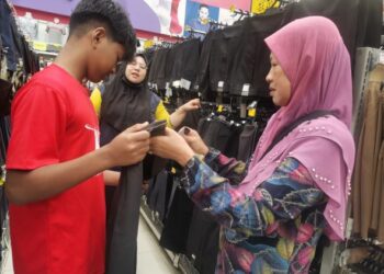ROHANI  Che Ka turut melihat pakaian sekolah anaknya selepas menerima bantuan semasa program Kembali Ke Sekolah Anjuran Kelab Santuni Asnaf dan GKNK di Kubang Kerian di sini baru-baru ini. 
– UTUSAN/ROSALWANI CHE SOH