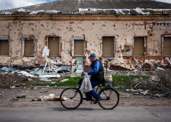 SEORANG lelaki menunggang basikal di hadapan rumah yang musnah di kampung Derhachi, utara Kharkiv, Ukraine.-AFP