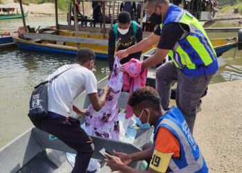 ROSLAN Abu Kassim (berdiri, kanan) membantu urusan mengangkat mayat kanak-kanak perempuan Orang Asli etnik Bateq ke atas bot penambang di jeti Kampung Kuala Tahan di Jerantut, Pahang. - FOTO /IHSAN PENDUDUK KUALA TAHAN