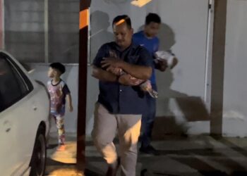 Anggota polis mengangkat bayi lelaki yang ditemukan di hadapan sebuah pangsapuri di Kuala Ibai, Kuala Terengganu, semalam.
