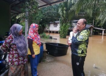 MOHAMAD Razif Abu Hassan mendukung bayinya, Muhamad Zikry selepas diselamatkan di rumah pengasuh yang dinaiki air di Kampung Kemat, Hulu Terengganu, semalam. - UTUSAN/NOOR HAYATI MAMAT