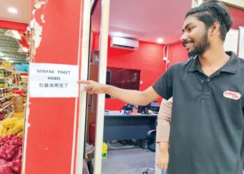 SEORANG pekerja kedai pemborong minyak masak menunjukkan nota pemberitahuan kehabisan minyak masak peket di Seremban, Negeri Sembilan, semalam.