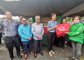 SANDREA Ng Shy Ching (empat dari kanan) menyerahkan beg plastik biodegradable kepada peniaga dan pengunjung di Tapak Bazar Ramadan Stadium Perak di Ipoh hari ini. - UTUSAN/LIYANA RAMLI