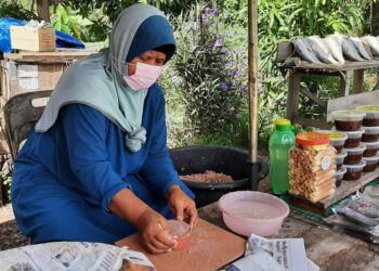 AINI Abd. Majid membuat belacan bersebelahan kedainya yang menjual pelbagai barangan makanan tradisional. – UTUSAN/AMRAN MULUP