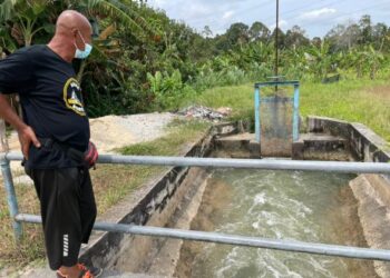 SEORANG petani melihat pelepasan air dari Chamber Gong Nangka untuk mengairi kawasan bendang yang kering-kontang di sekitar Gaal, Pasir Puteh, Selasa lalu. - UTUSAN/TOREK SULONG