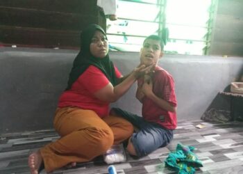 NOOR Azila Abd. Rahim memeriksa kesihatan Muhammad Amirul Haiqal Mohamad Shahizan yang mengidap bengkak lendir di muka dan leher di Kampung Sungai Badak, Gurun, Sungai Petani hari ini. - ABD. RAZAK OSMAN