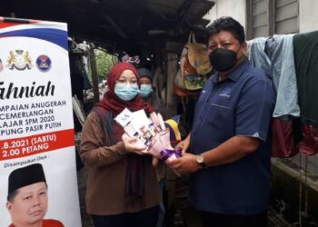 MAZLAN Bujang (kanan) menyampaikan sumbangan kepada Nur Asida Saiful Hadi yang mencatat keputusan cemerlang dalam SPM 2020 di Kampung Pasir Putih di Pasir Gudang, Johor.