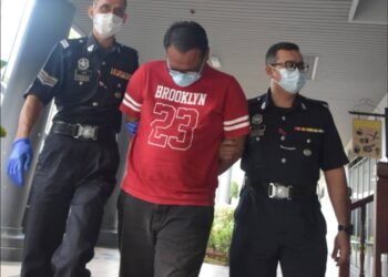 TERTUDUH diiringi anggota polis setelah dibenarkan diikat jamin sebanyak RM1,600 selepas didakwa menumbuk kepala isterinya yang juga seorang pegawai perubatan di Mahkamah Majistret di Ayer Keroh, Melaka. UTUSAN/ DIYANATUL ATIQAH ZAKARYA
