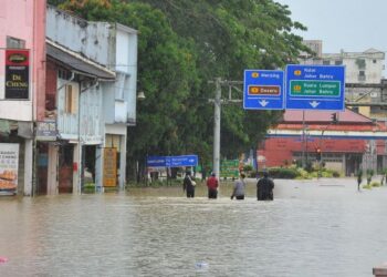 BEBERAPA penduduk meredah banjir di tengah bandar Kota Tinggi, Johor.