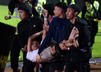 SEORANG penonton dibawa ke tempat selamat selepas kekecohan tercetus di Stadium Kanjuruhan, Malang.-AFP