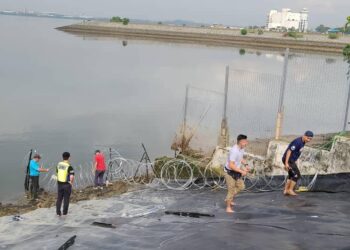 Pihak polis memasang kawad berduri di tebing Selat Tebrau berhampiran Kompleks Kastam, Imigresen dan Kuarantin (CIQ), Bangunan Sultan Iskandar di Johor Bahru. -IHSAN PDRM