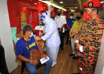 YAHAYA Madis (kanan) dan Dr. Aman Rabu (dua dari kanan) melihat seorang penduduk menerima suntikan vaksin ketika Program Vaksin Bergerak kerjasama JBPM Johor dan JKNJ di Taman Jaya, Skudai, Johor. - FOTO/RAJA JAAFAR ALI