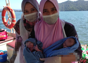 NUR Shaffriza Mohd. Shaffril (kiri) dan rakan pasukan perubatan yang membantu kelahiran bayi kembar di dalam bot ambulans yang sedang bergerak melalui Tasik Banding di Gerik, Sabtu lalu. - IHSAN NUR SHAFFRIZA