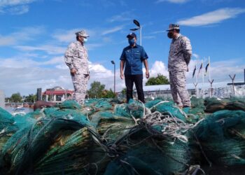 SHAHRIZAN Raman (kanan) memberi penerangan mengenai rampasan 241 bubu naga kepada Abdul Yunus Jamahri (tengah) di Jeti Zon Maritim Kuala Kurau di Parit Buntar, Perak, hari ini. - UTUSAN/WAT KAMAL ABAS