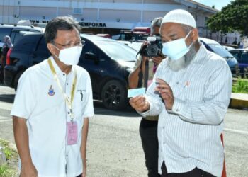 MOHD. Shafie Apdal (kiri) semasa menunaikan tanggungawab mengundi di Sekolah Kebangsaan Bubul, Semporna, Sabah, hari ini.