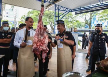 RAZARUDIN Husain (dua dari kiri) memotong daging lembu korban di Masjid Bukit Aman pagi tadi. - FOTO/AFIQ RAZALI