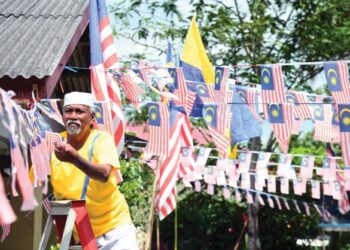 BEKAS peneroka Felda, Man Jusoh, 67, memasang bendera Malaysia sempena kempen kibar Jalur Gemilang sempena bulan kebangsaan di Felda Chuping, Perlis . - UTUSAN/IZLIZAN OTHMAN