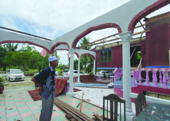 SALLEH Mustaram memerhatikan bahagian beranda dan ruang tamu rumahnya yang musnah dalam kejadian ribut di Tanjong Karang, Selangor, awal pagi semalam. – UTUSAN / MOHAMAD ATHIR ISMAIL