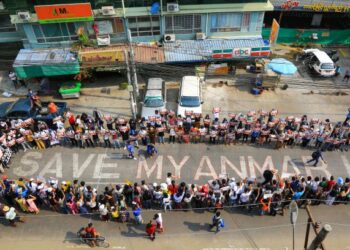 PENUNJUK perasaan berdiri mengelilingi mesej atas jalan yang bertulis 'Selamatkan Myanmar’ ketika menyertai demonstrasi di pekan Hlaing di Yangon, Myanmar. - AFP