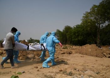 PETUGAS perubatan yang lengkap mengenakan pakaian perlindungan diri (PPE) mengusung mayat pesakit Covid-19 untuk dikebumikan di New Delhi, India. - AFP
