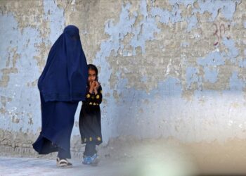 SEORANG wanita mengenakan burka berjalan bersama seorang kanak-kanak di sebuah jalan di Kabul. - AFP