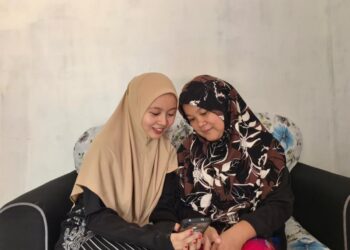 Nur Faizathul Anis (kiri) berkongsi kegembiraan dengan ibunya semasa menyemak keputusan SPM secara dalam talian di Beaufort, Sabah semalam.